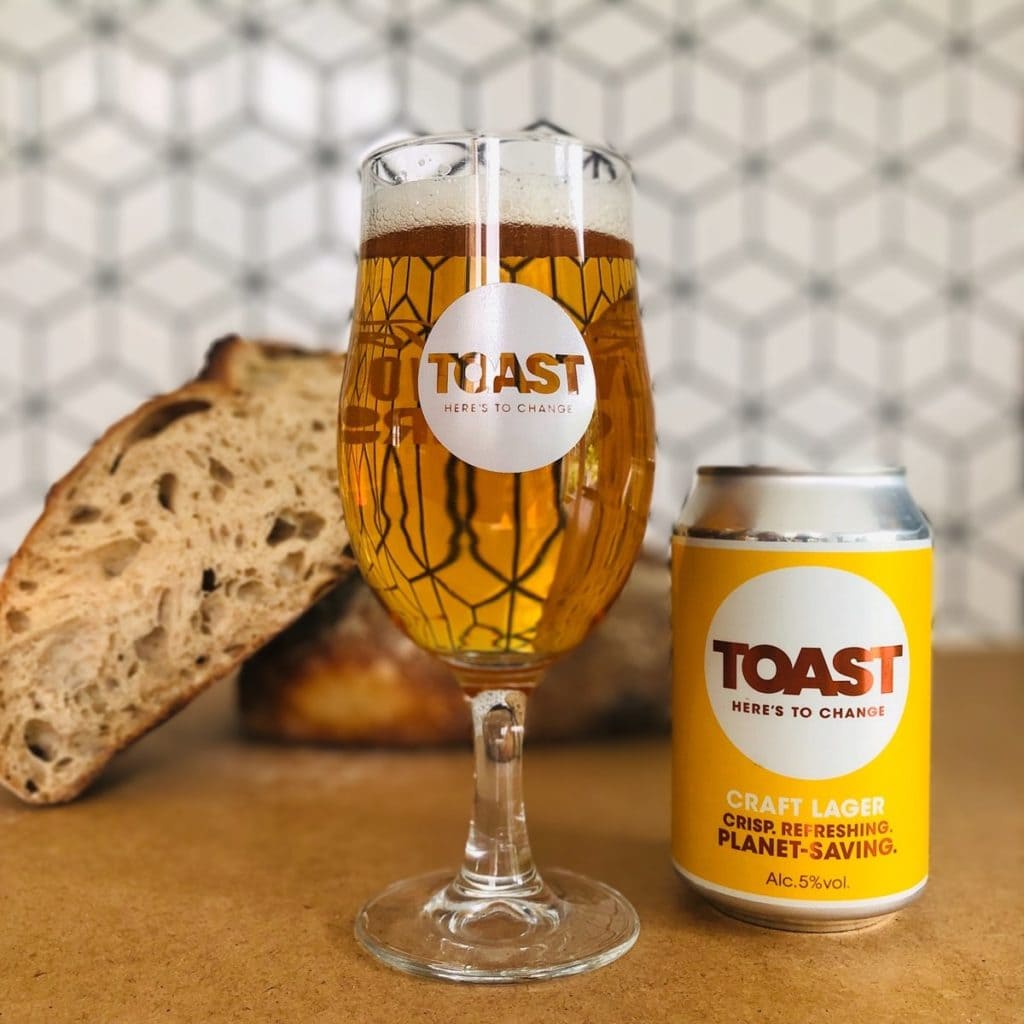 A pint of craft lager with the Toast logo next to a can of Toast craft lager with bread in the background. 