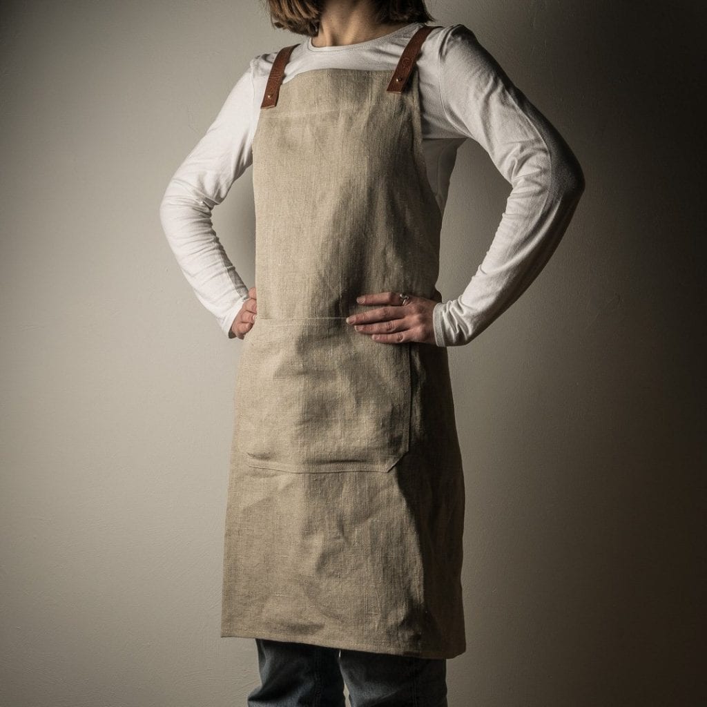 The linen apron worn by a person with their hands on their hips