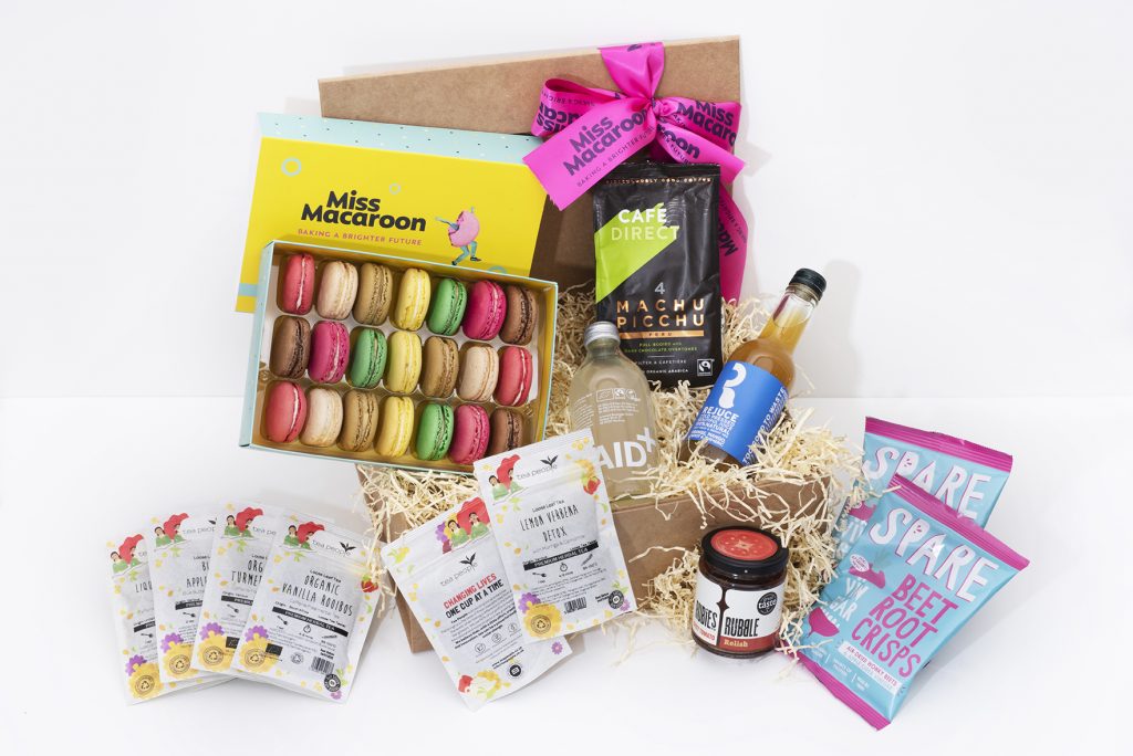 A gift box showing its contents including macaroons, drinks, and snacks