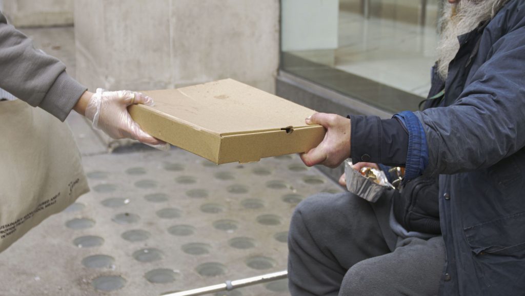 A cardboard food parcel is handed from one person to another, their faces out of shot