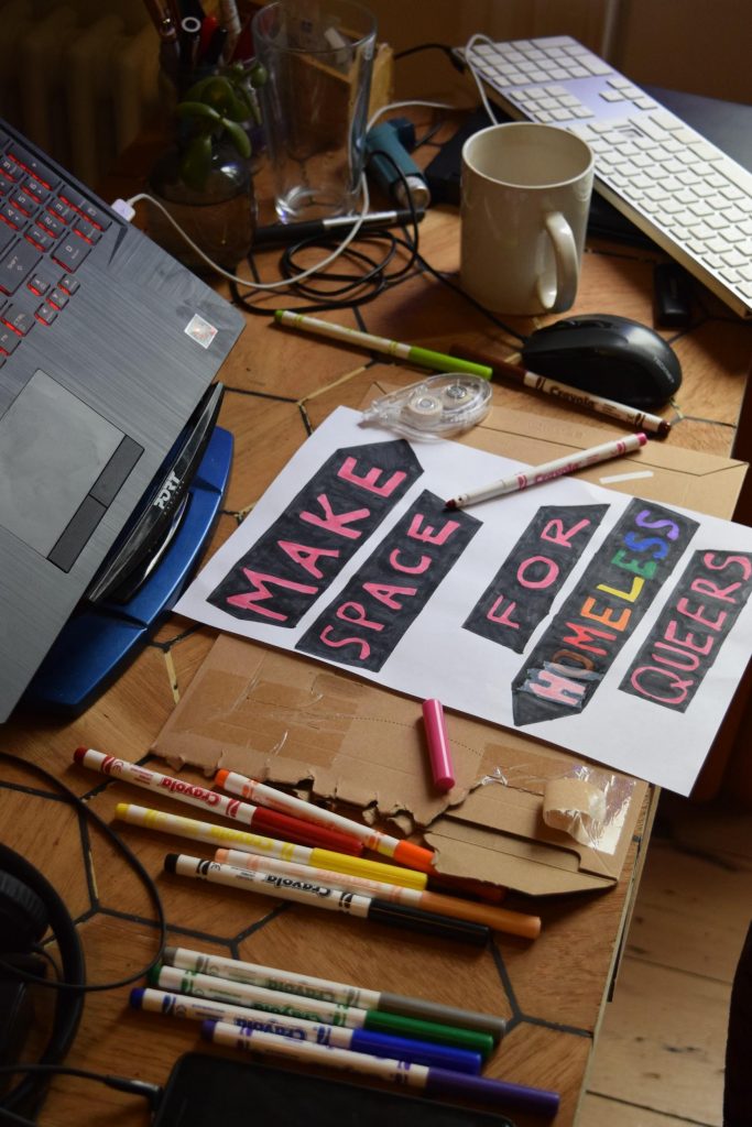 A poster on a desk with a laptop in the background and pens to one side