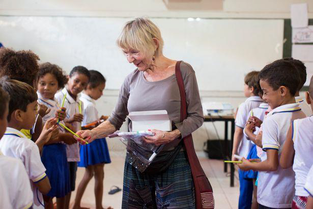 A volunteer gives away pencils to school children