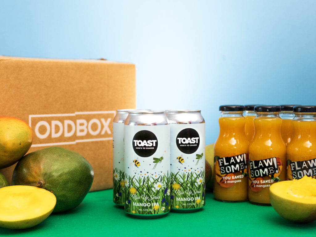 Toast and Flawsome Mango IPA with an Oddbox box in the background and mangoes in the foreground