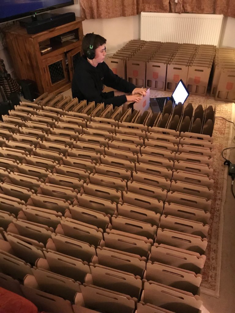 Founder of Crumbs, Morgan's son helping to organise their packaging – rows and row of cardboard are in the foreground.