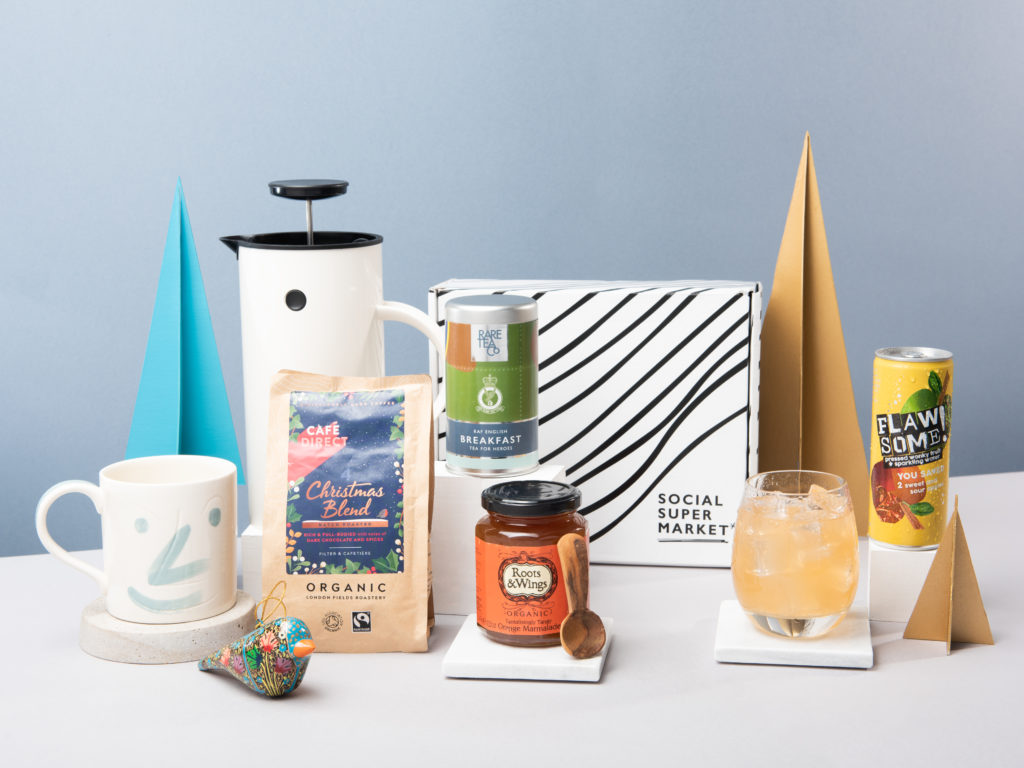 The Social Supermarket gift box surrounded by a jar of marmalade, a tin of tea, coffee and an apple juice drink.