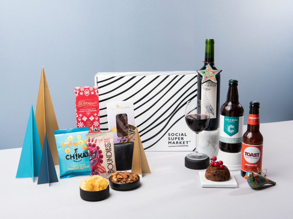 The Snowy Pine Gift Box products on display, including a range of snacks and drinks, surrounded by festive decorations.