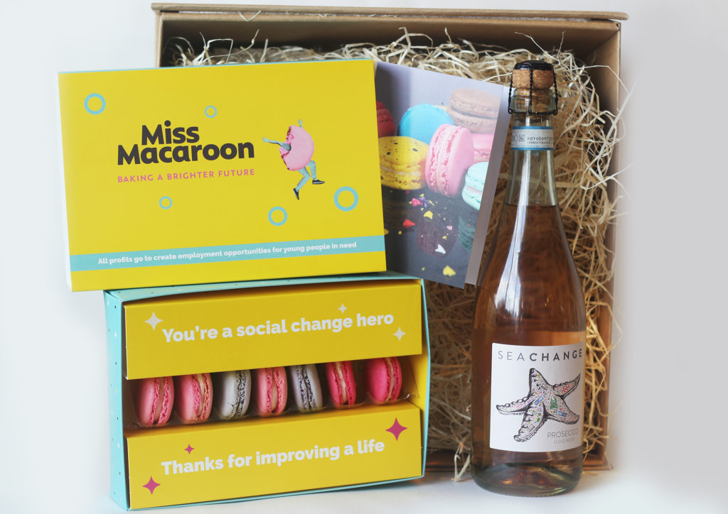 A gift box with a box of macaroons and a bottle of Sea Change prosecco rosé