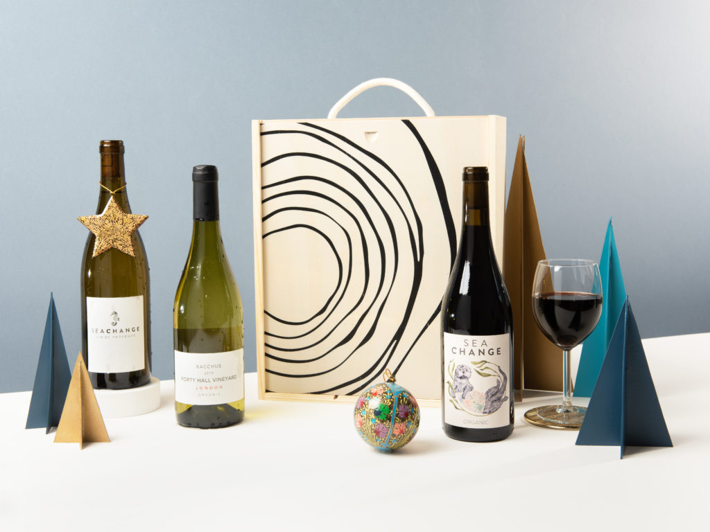 A display of 3 wines against a wooden box and surrounded by festive Christmas decorations