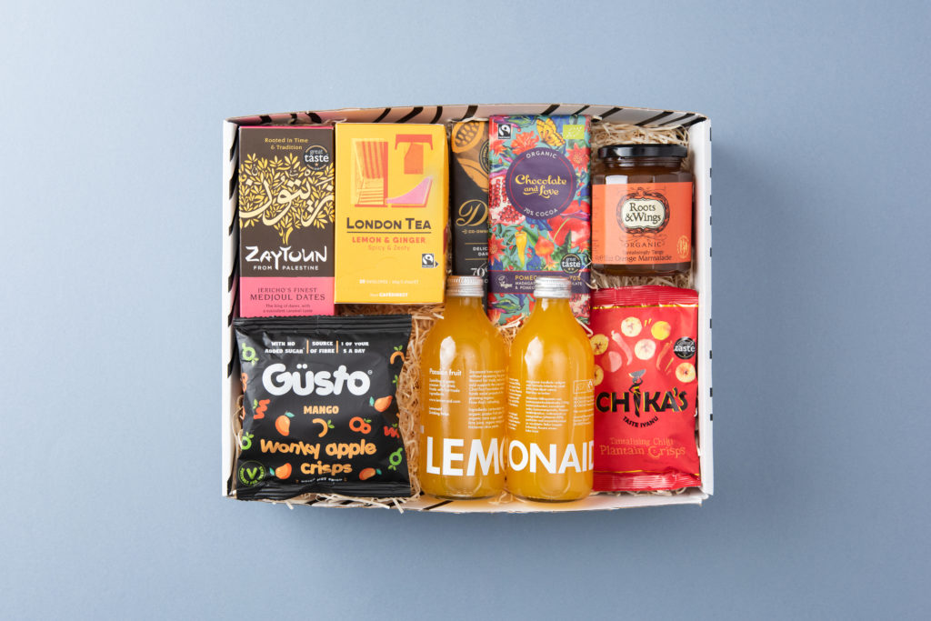 The Red Majestic Christmas gift box shown as if the box has just been opened with its contents inside including Lemonaid Passionfruit, Güsto snacks and London Tea Company tea, among others.