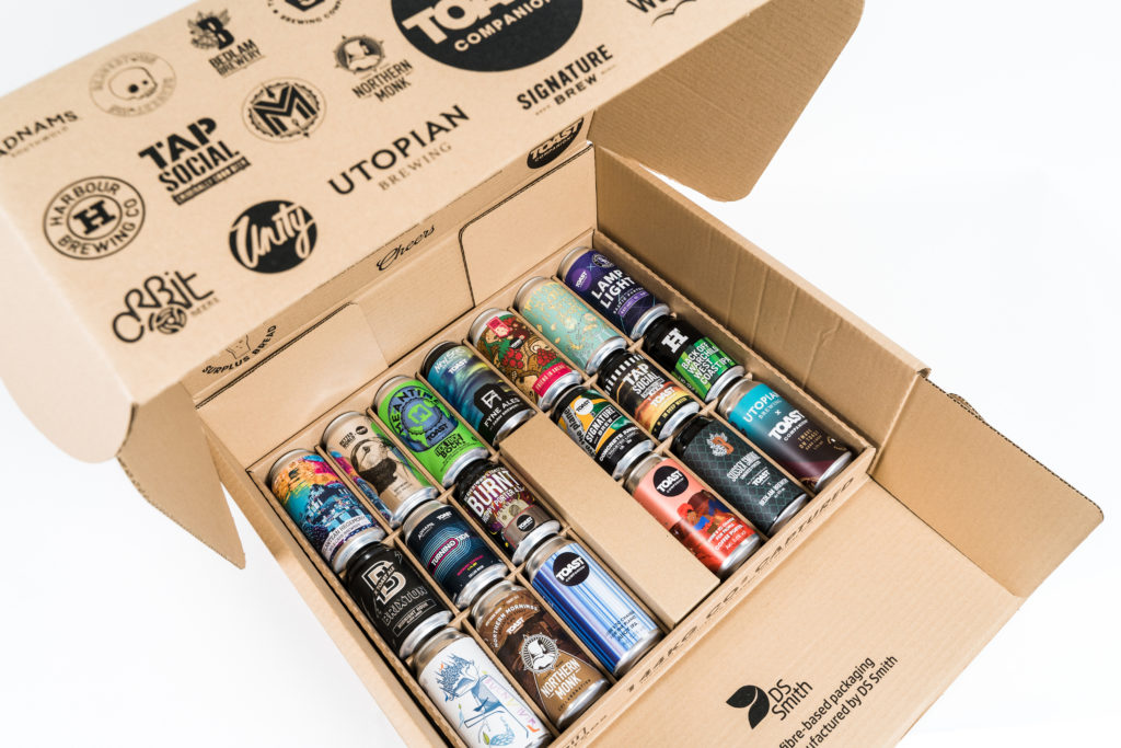 Photo of the beer can layer of the Companion Series gift box, with the logos of all of the collaborators brinted onto the brown cardboard box lid. Photographed on a white background.