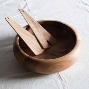 A photo of the Erno salad bowl with salad servers. Photographed on a white linen background.