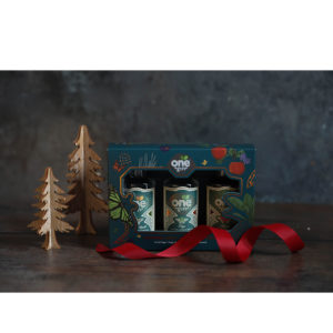 A photo of One Gin's gift set against a greyish blue background with gold christmas tree models next to them and red ribbon in the foreground.