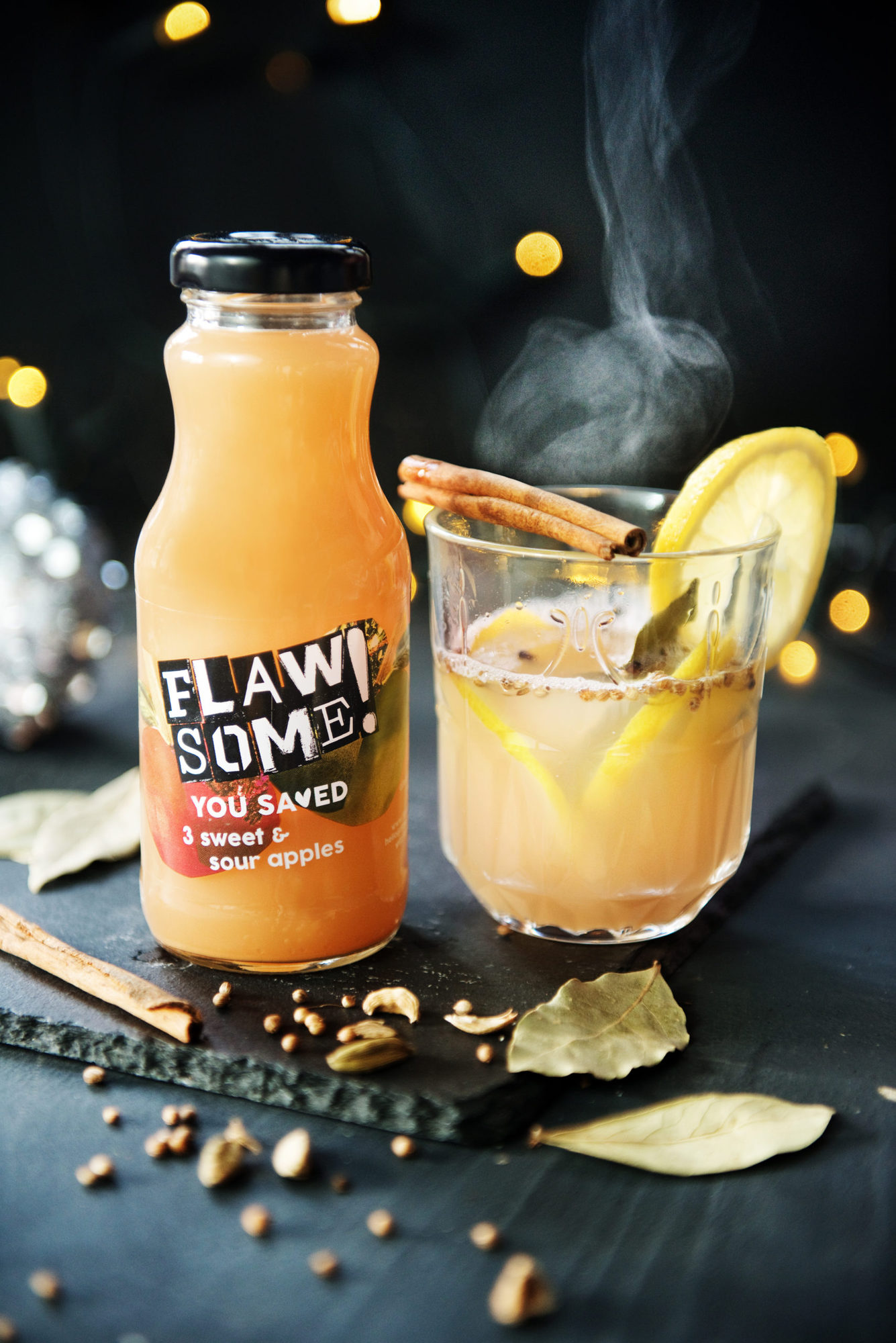 A glass of mulled gin next to a glass bottle of Flawsome!