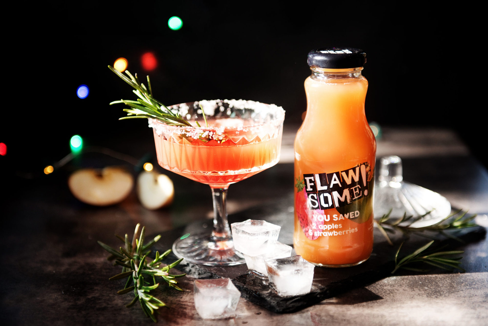 A Strawberry Sparkler cocktail next to a bottle of Flawsome! Drinks juice