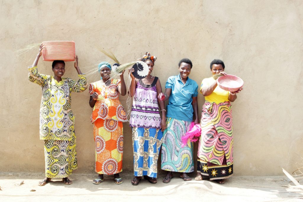 A group of female artisans in Rwanda, Africa in a row with woven baskets