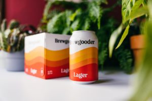 A can and pack of Brewgooder Lager among plants