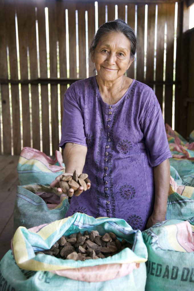 A female farmer holding a handful of nuts out to the camera