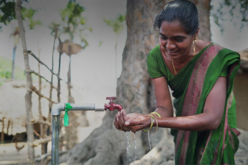 A woman puts her hand under an outdoors tap