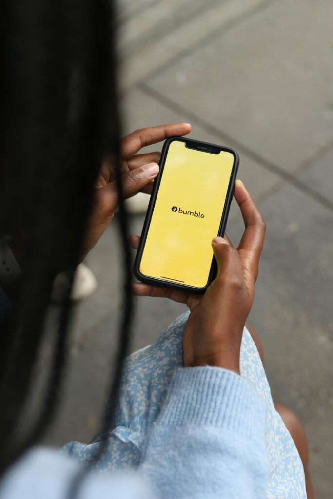 A woman holds a phone open to the Bumble app
